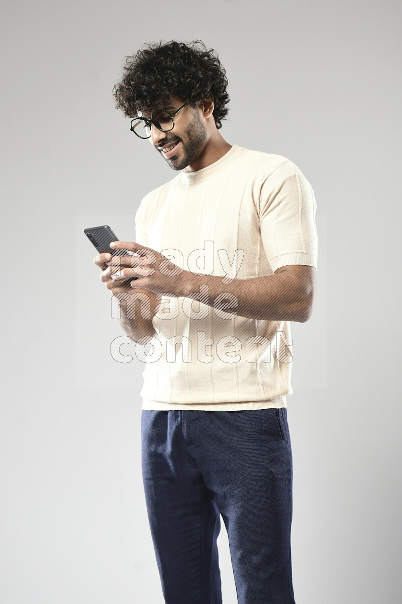 رجل يرتدي ملابس كاجوال يرسل رسائل نصية علي الهاتف علي خلفية بيضاء