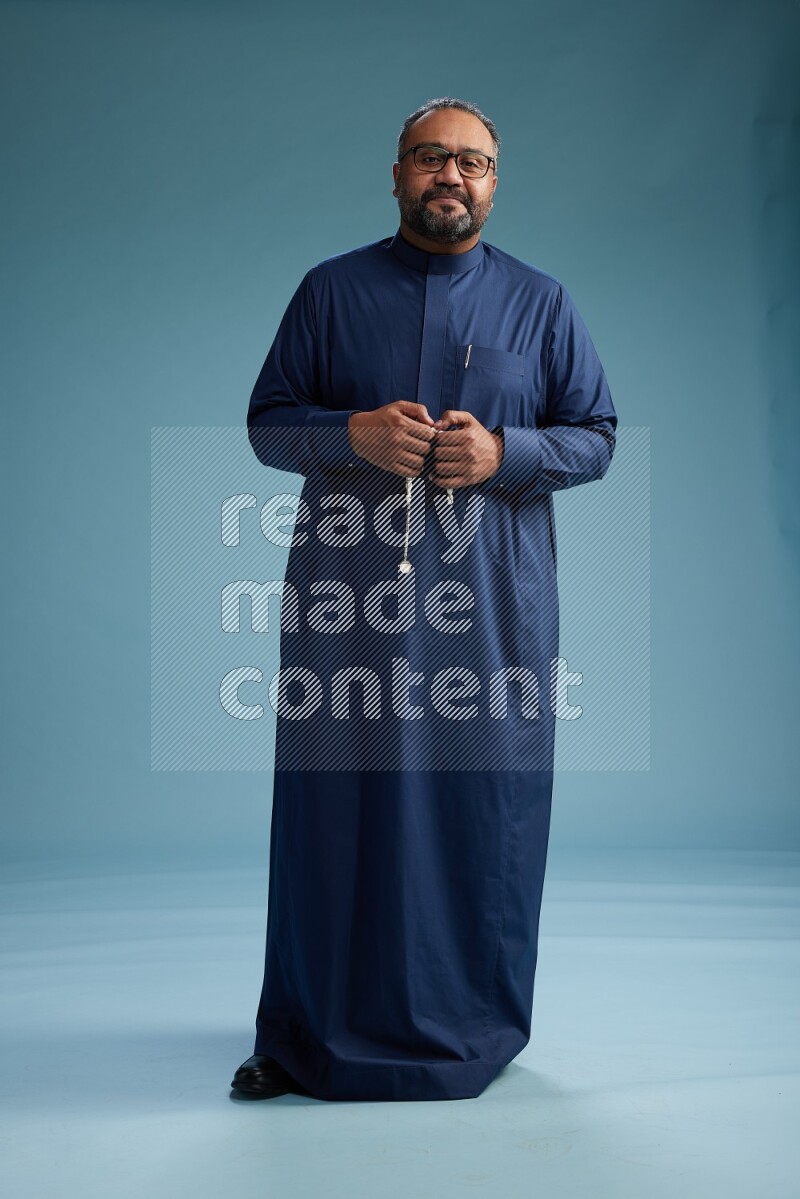 Saudi Man without shimag Standing Interacting with the camera on blue background