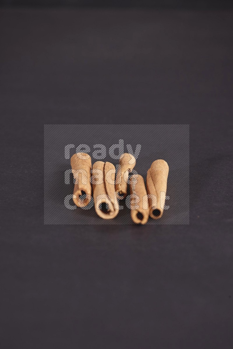 Cinnamon sticks stacked on black flooring