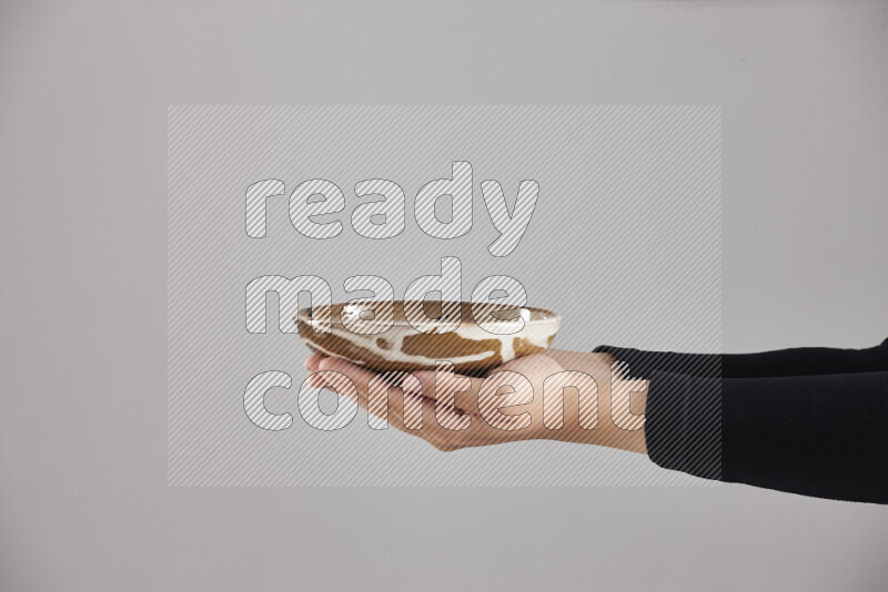 A woman in black abaya holding different pottery essentials in different positions