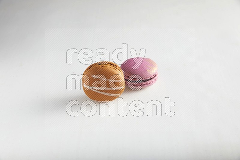 45º Shot of of two assorted Brown Irish Cream, and Purple Strawberry macarons on white background