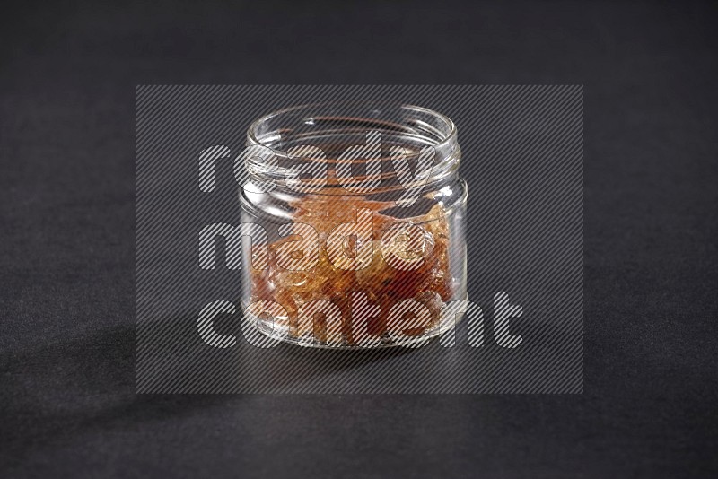 A glass jar full of gum arabic on black flooring
