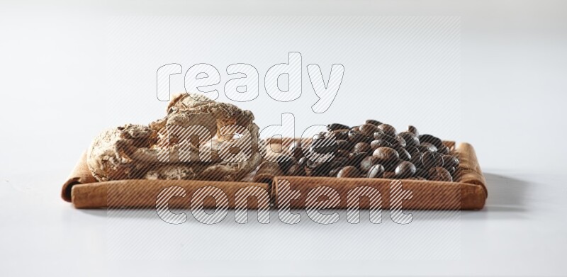 مربعان من أعواد القرفة ممتلئان بحبوب القهوة والزنجبيل المجفف علي خلفية بيضاء