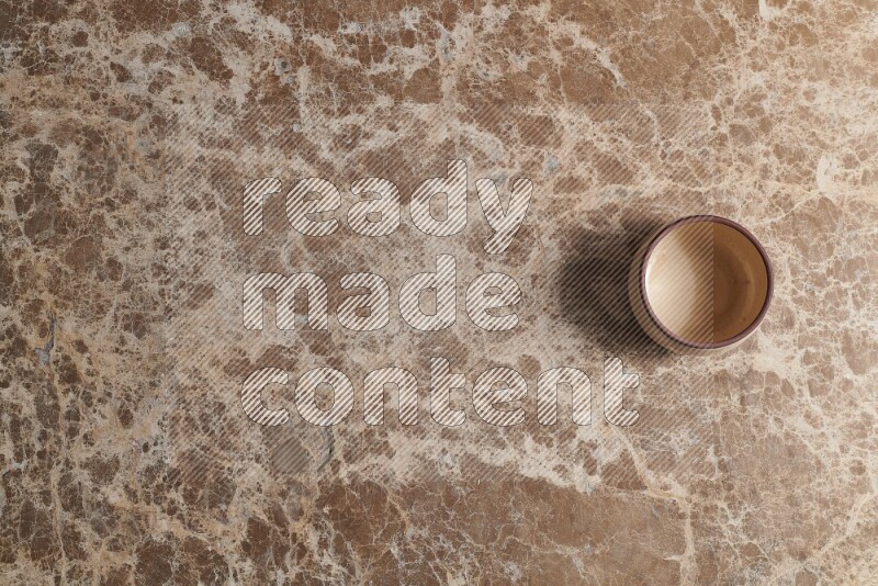 A beige pottery bowl on beige marble background