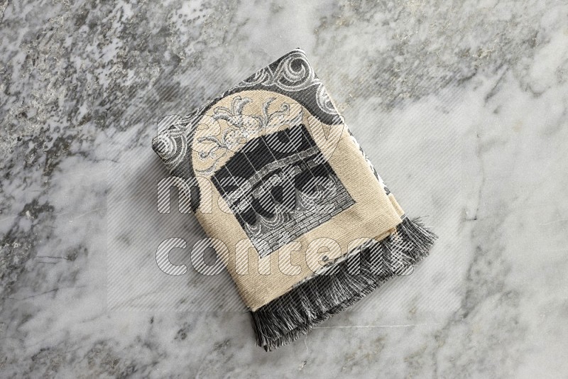 A prayer rug with different elements such as quran and prayer beads on grey marble background