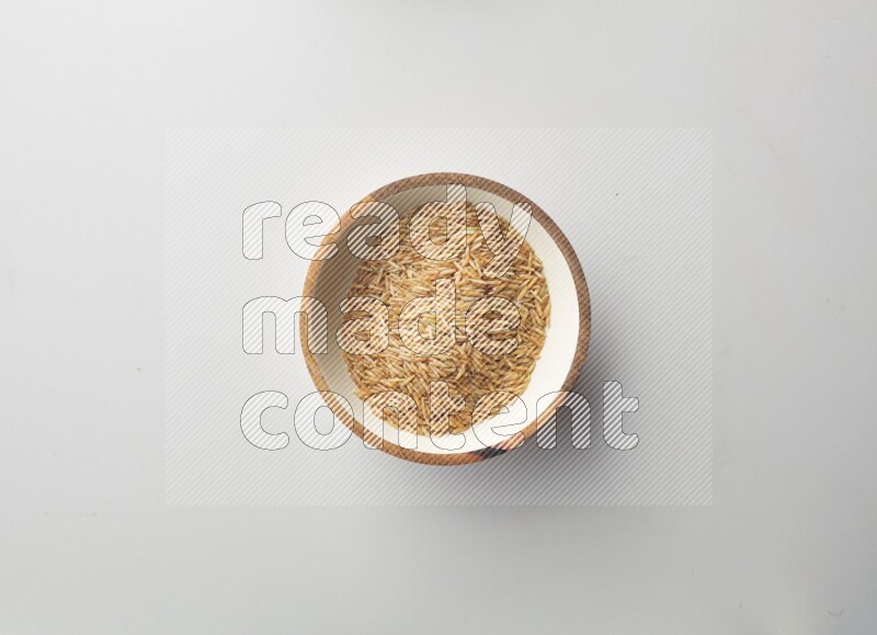 Top-view shot of long grain brown rice in a container on white background
