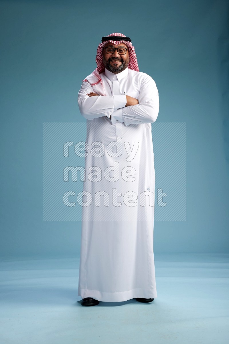 Saudi Man with shimag Standing Interacting with the camera on blue background