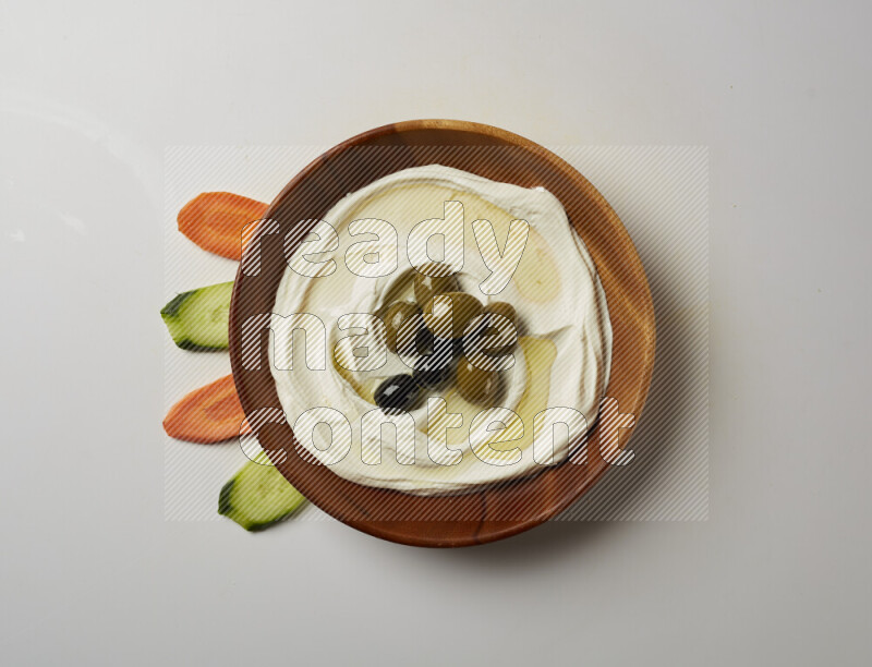 Lebnah garnished with whole olives in a wooden plate on a white background