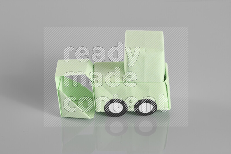 Origami bulldozer on grey background