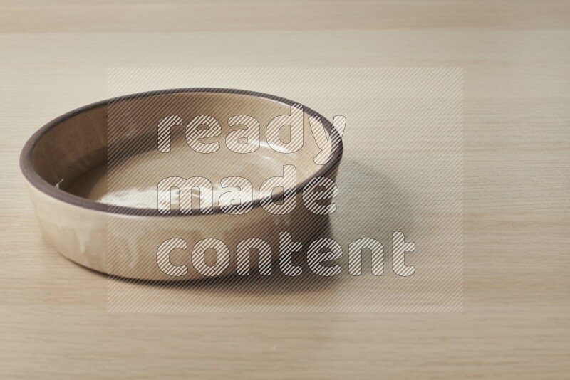 A beige pottery oven plate on light wooden background