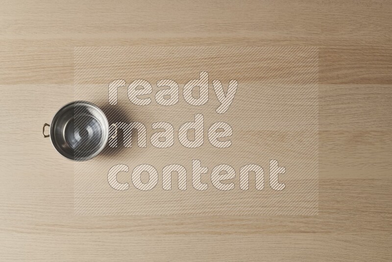 وعاء نحاسي صغير على خلفية خشبية فاتحة