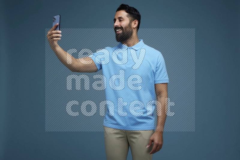 Man Taking a Selfie in a blue background wearing a Blue shirt