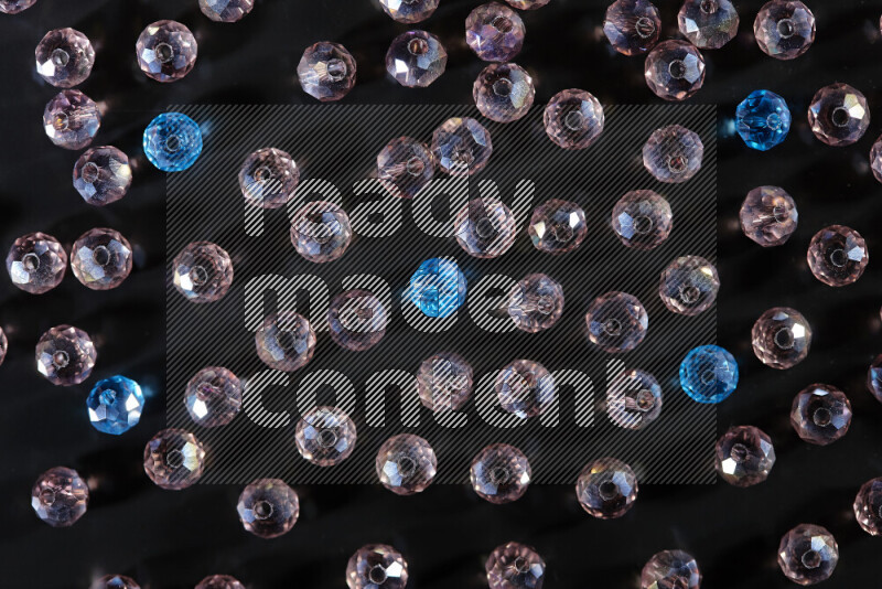Rose and blue transparent crystal beads scattered on a black background