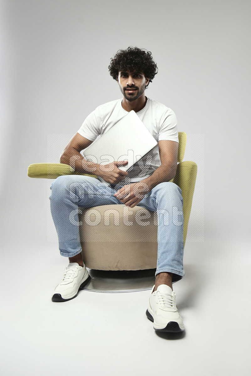 A man wearing casual sitting on a chair holding a laptop on white background