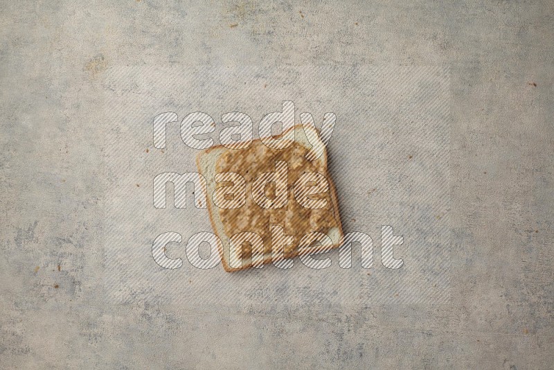 Crunchy peanut butter on a white toast on a light blue textured background