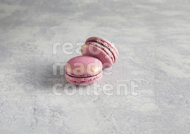 45º Shot of two Purple Strawberry macarons on white  marble background