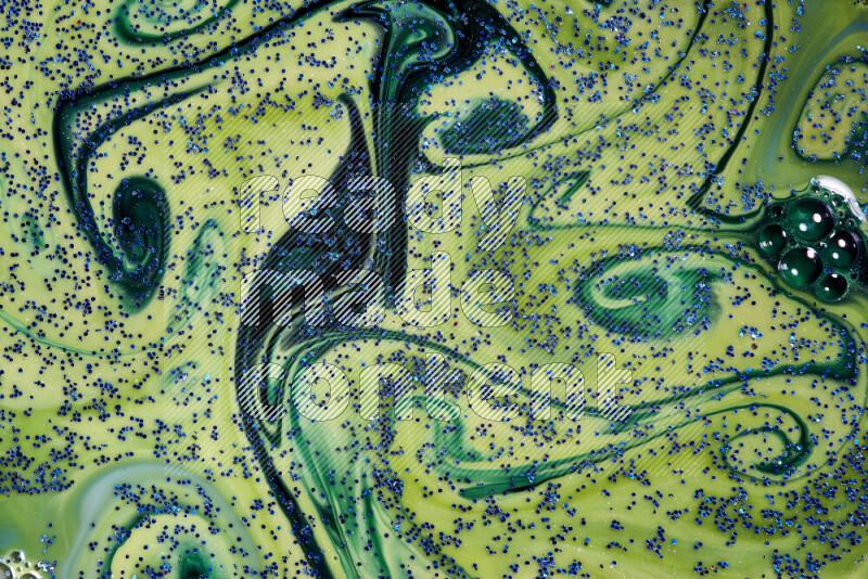 A close-up of sparkling blue glitter scattered on swirling blue and green background