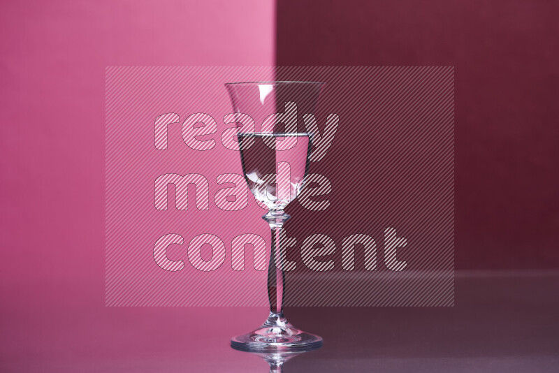 The image features a clear glassware filled with water, set against pink and dark red background