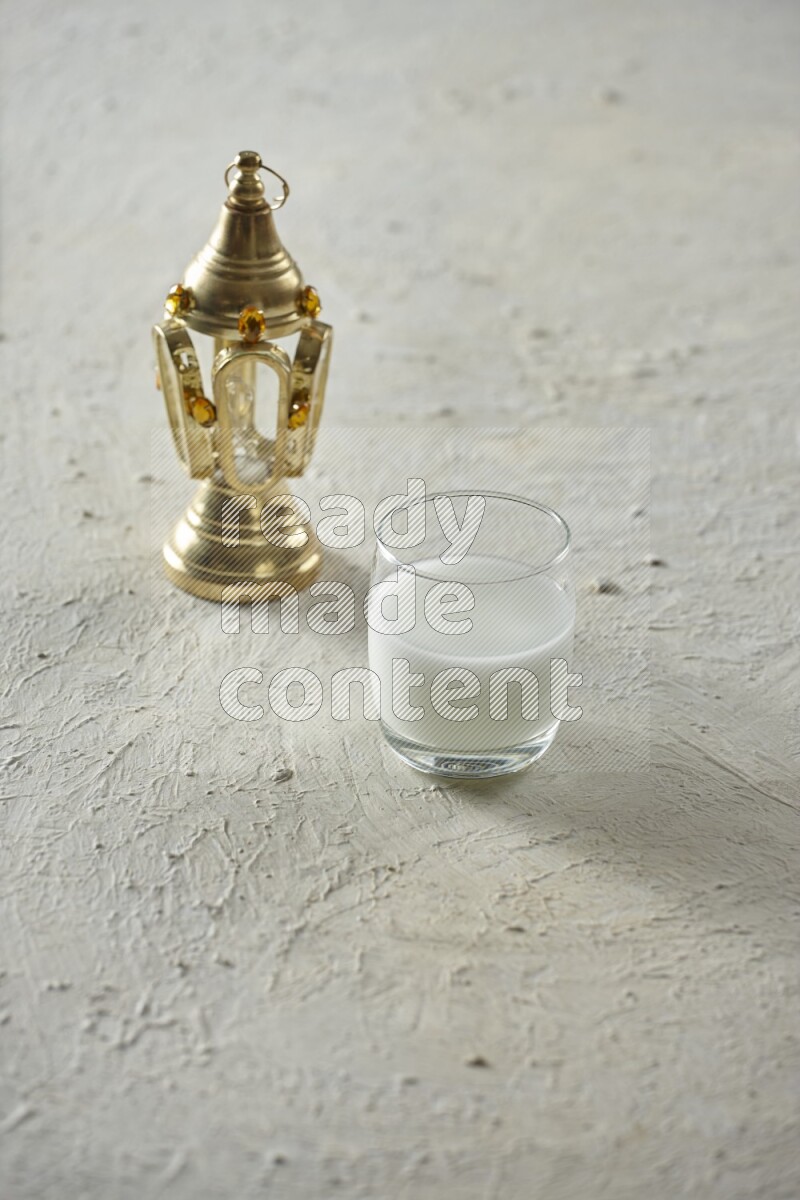 A golden lantern with different drinks, dates, nuts, prayer beads and quran on textured white background
