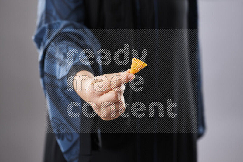 Woman in abaya holding different kinds of snacks in different positions