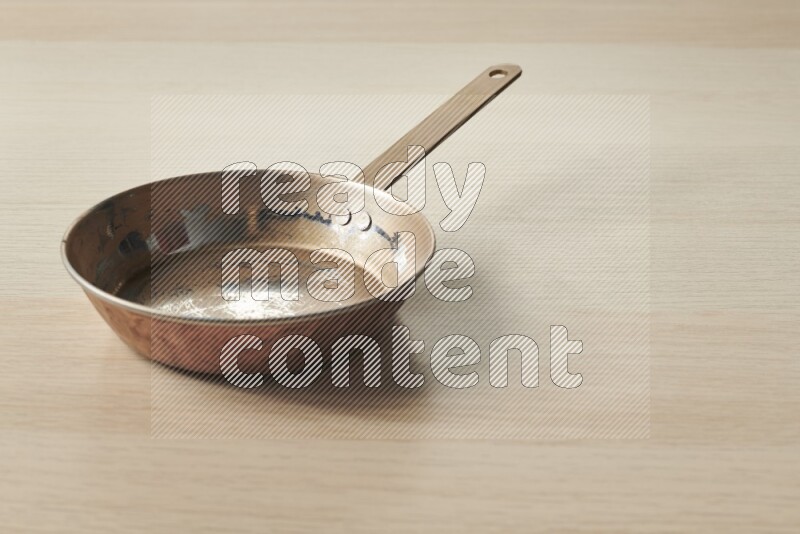 A small copper pan on light wooden background