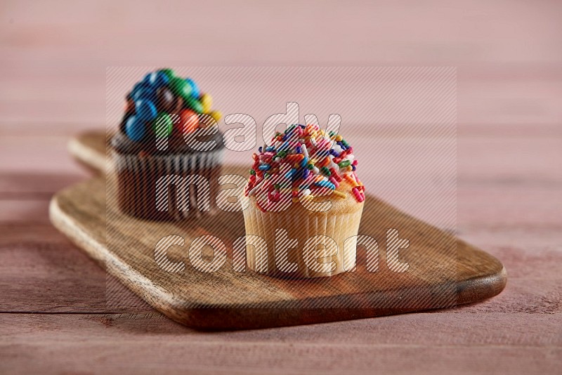 Vanilla mini cupcake topped with sprinkles on a wooden board