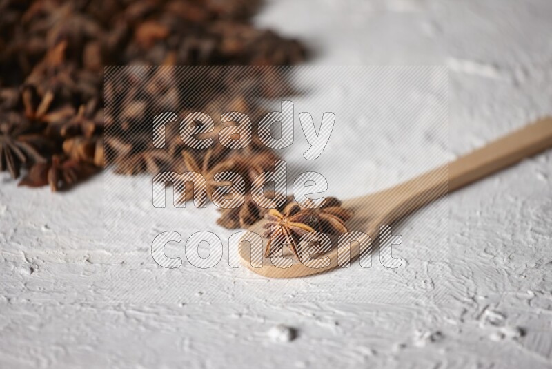 Star anise on a wooden spoon and spreading on the background on a white flooring
