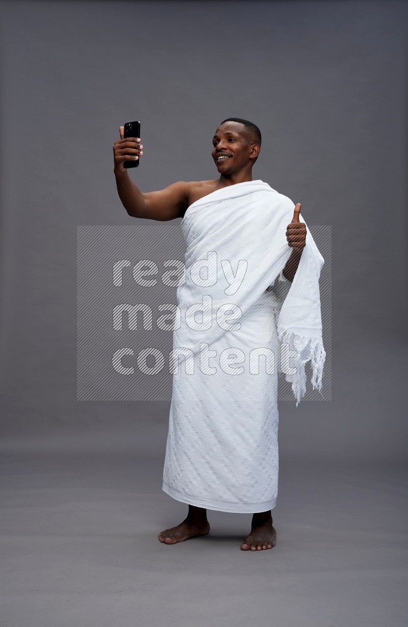 A man wearing Ehram Standing taking selfie on gray background