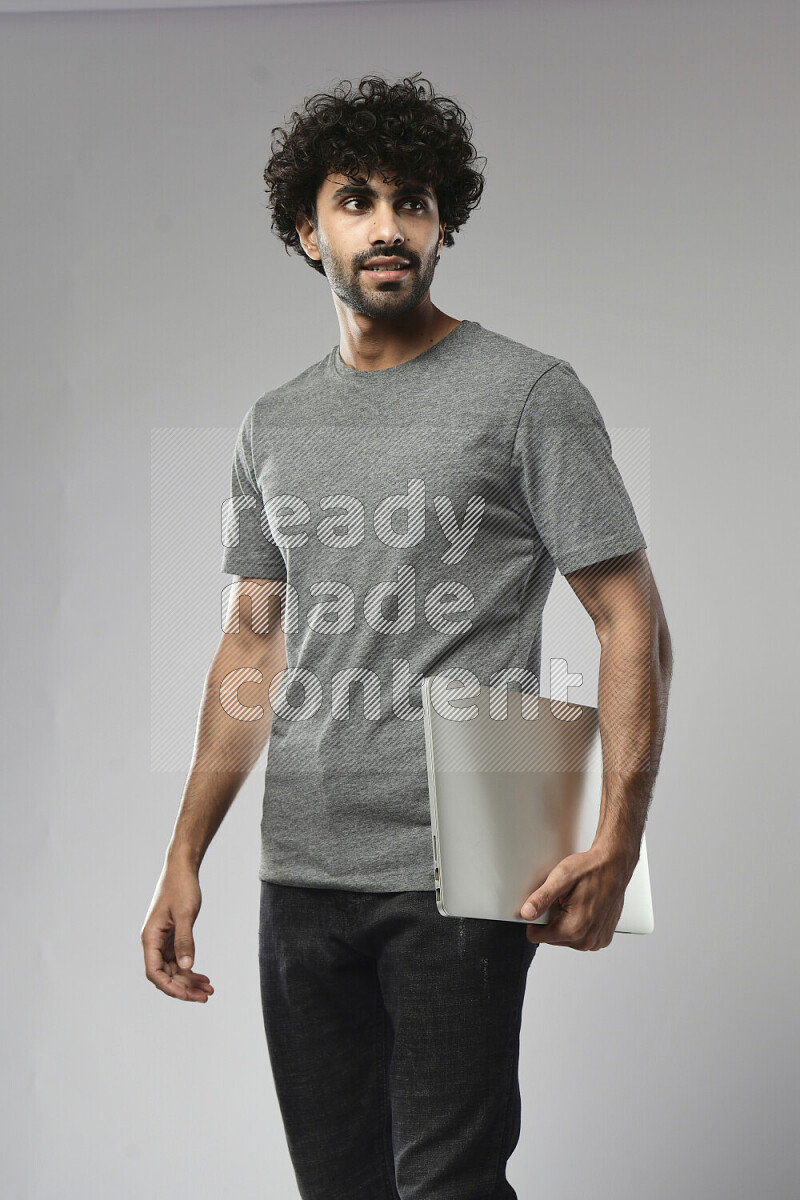 A man wearing casual standing and holding a laptop on white background