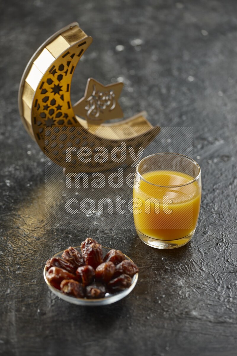 A wooden golden crescent lantern with different drinks, dates, nuts, prayer beads and quran on textured black background