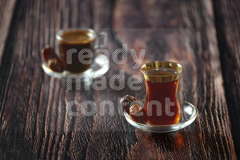 كوب زجاجي من الشاي مع التمر والقهوة على خلفية خشبية