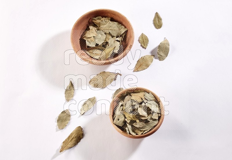 2 wooden bowls filled with laurel bay on white flooring in different angles