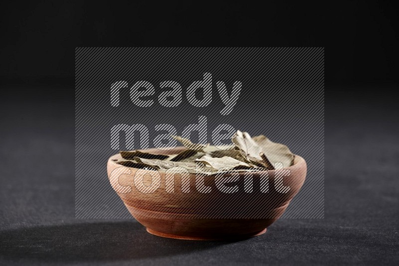 A wooden bowl filled with laurel bay on black flooring in different angles