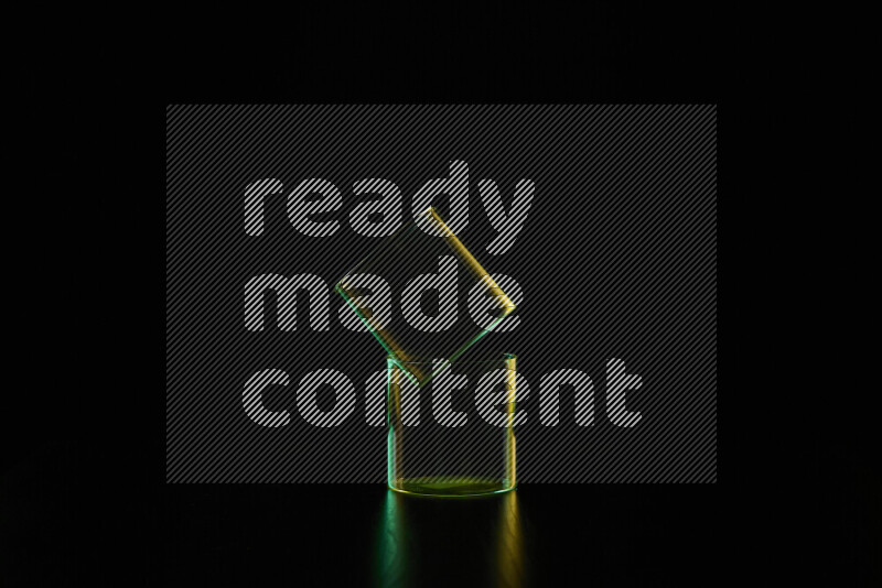 Glassware with rim light in green and yellow against black background