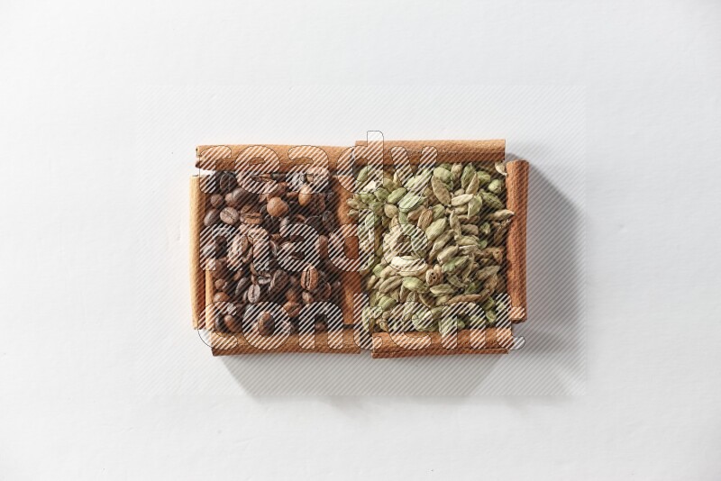 مربعان من أعواد القرفة ممتلئان بحبوب الهيل وحبوب القهوة علي خلفية بيضاء