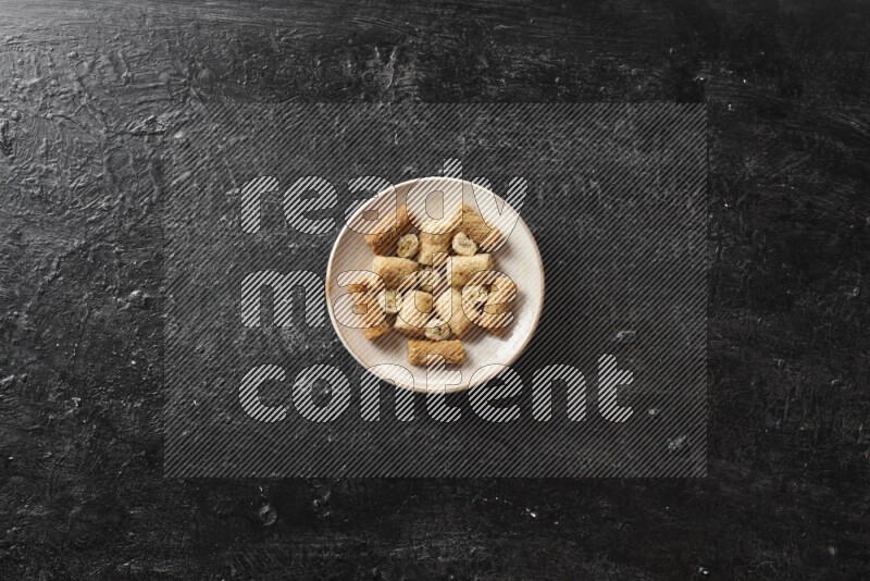 حلويات شرقية في أطباق فخارية علي خلفية سوداء خشبية