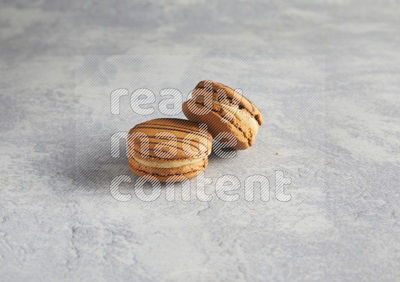 45º Shot of two light brown  Almond Cream macarons  on white  marble background