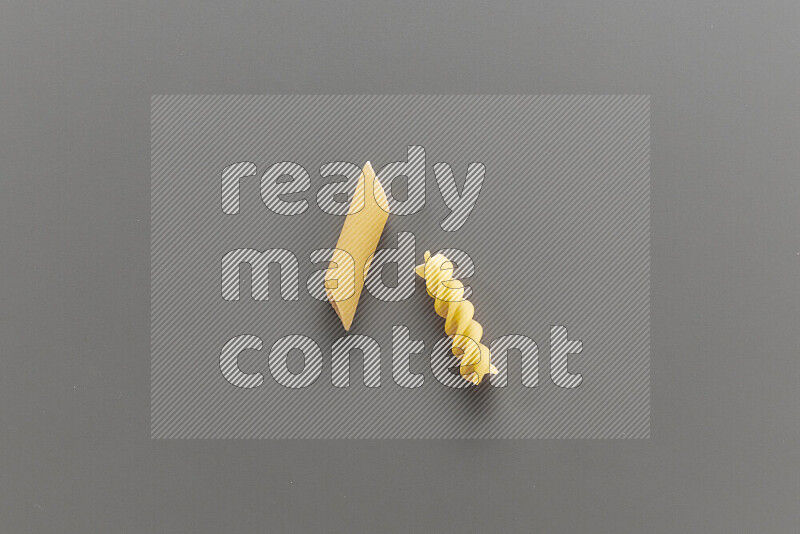 Penne pasta with other types of pasta on grey background