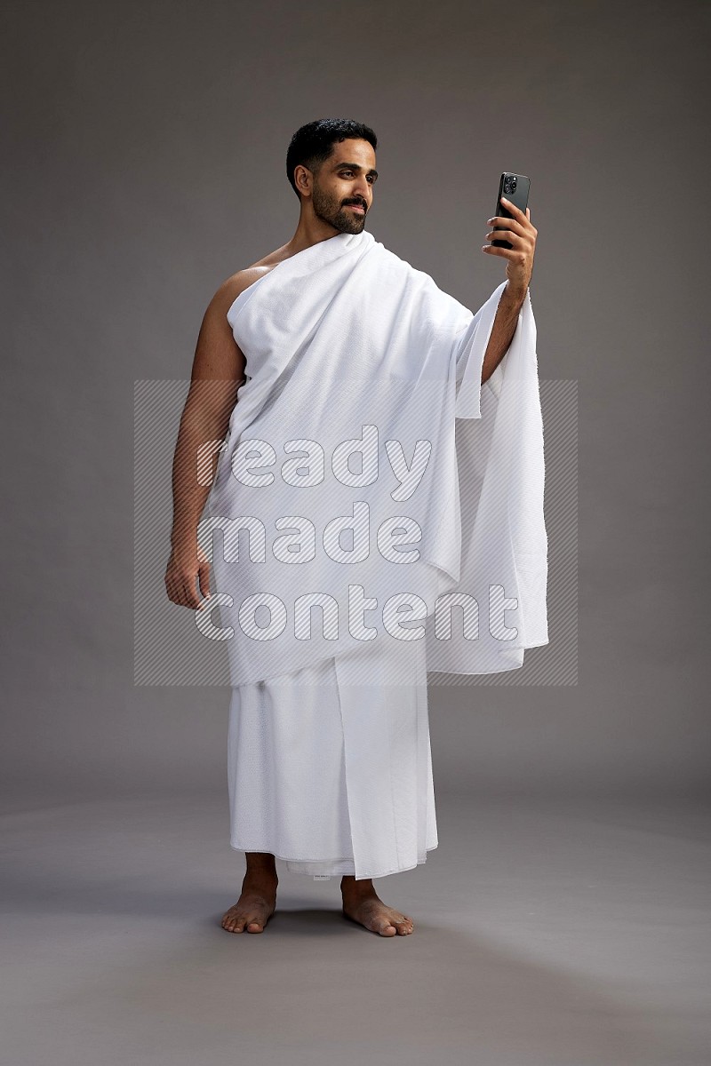 A man wearing Ehram Standing taking selfie on gray background