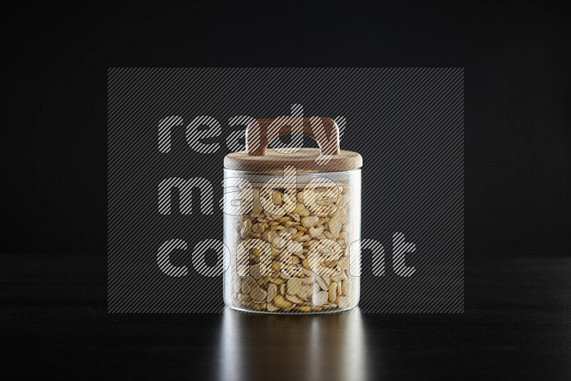 Crushed beans in a glass jar on black background