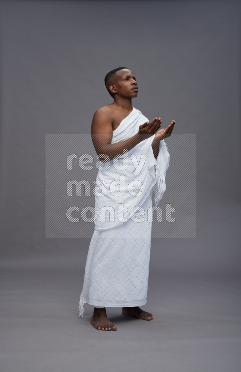 A man wearing Ehram Standing dua'a on gray background