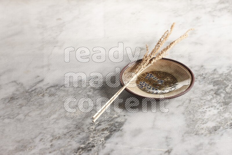 Wheat stalks on decorative pottery plate on grey marble background