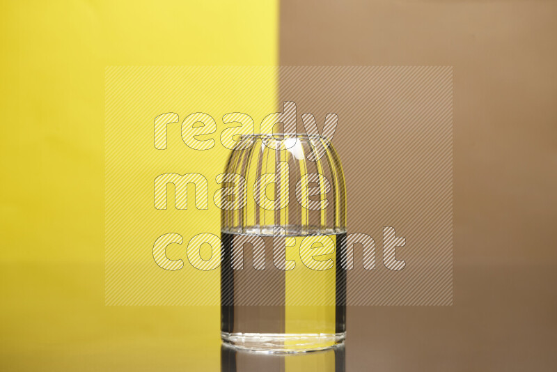 تظهر الصورة أواني زجاجية ممتلئة بالماء موضوعة على خلفية من اللونين الأصفر والبيج