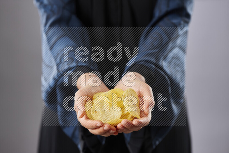 Woman in abaya holding different kinds of snacks in different positions