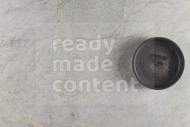 A black pottery oven bowl on grey marble background