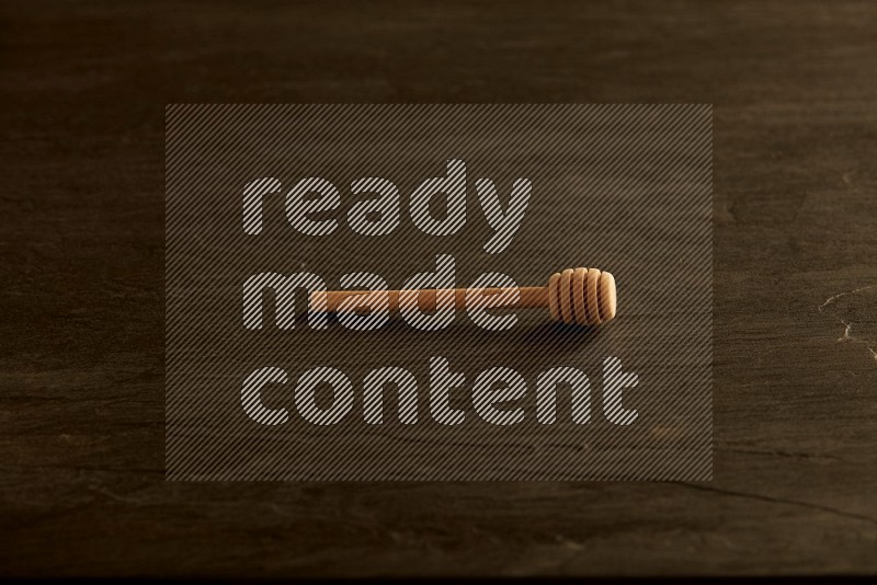 Wooden honey dipper on black slate background