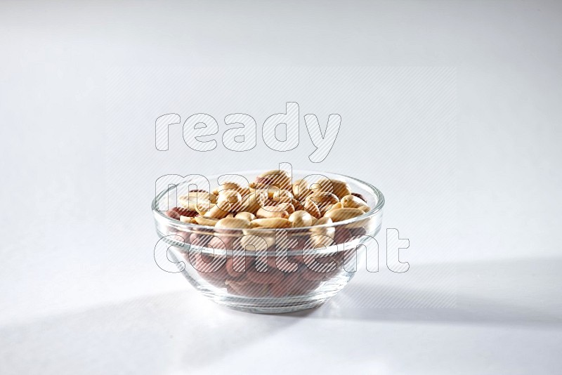 A glass bowl full of peeled peanuts on a white background in different angles