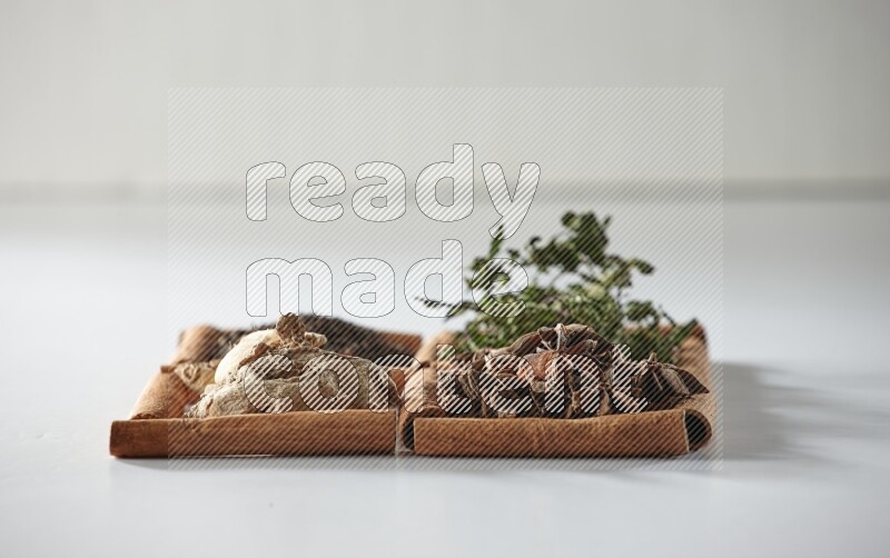 4 مربعات من أعواد القرفة ممتلئة بالشاي والنعناع واليانسون والزنجبيل على أرضية بيضاء