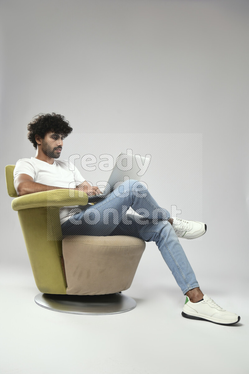 A man wearing casual sitting on a chair working on a laptop on white background