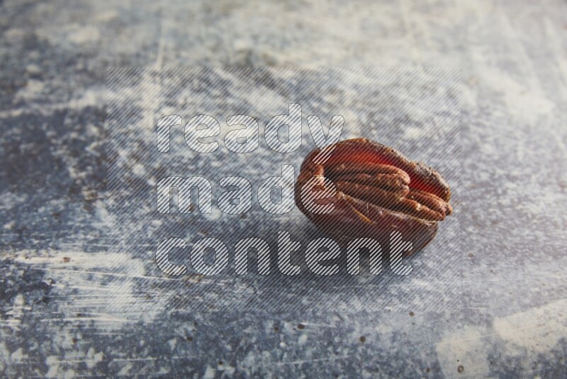 pecan stuffed madjoul date on a rustic blue background